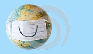 Planet Earth with a smile on protective medical face mask. Copyspace. Minimal concept corona virus epidemic danger. Global