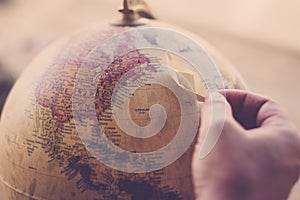 Planet earth on sphere with hand and little paper boat for travel and dream concept - move around the world with cruise ship and