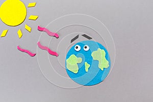 The planet earth and the sun are carved out of felt. Gray background. Copy space. Flat lay. The concept of global warming