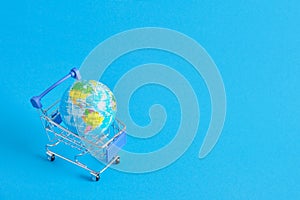 a planet earth in a supermarket shopping cart on blue background. copy space