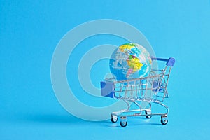 a planet earth in a supermarket shopping cart on blue background. copy space