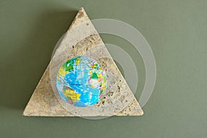 planet model on a triangular concrete podium on a green background