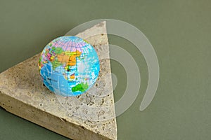 planet model on a triangular concrete podium on a green background