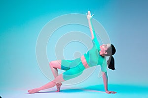 Plank. Young sportive woman training  on gradient studio background in neon light. athletic and graceful. Modern