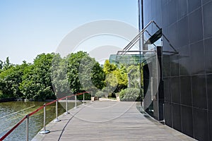 Planked path between modern building and pond in sunny summer