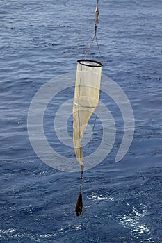 Plankton net on the blue water background. Science equipment for sampling of water organisms deployment.