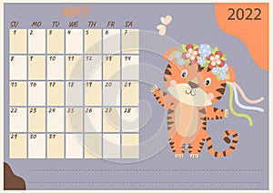 Planner calendar for May 2022. A cute tiger cub is dancing in a wreath of flowers with ribbons. Nearby butterflies. Year