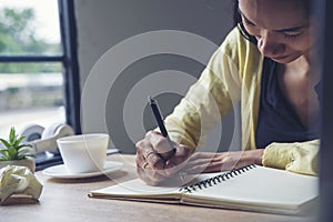Planner write meeting agenda at Calendar, work online at home. Hand of asian Woman planning daily appointment and note holiday