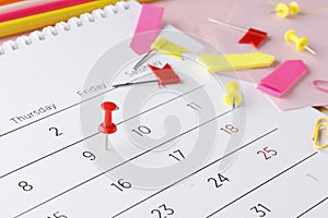 Planning calendar on a pink background with pins, pencils, stickers ..