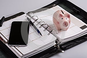 Planning concept - calendar, cellphone, pen, pig moneybox