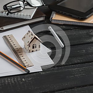 Planning of the construction of a house. Office desk with business objects - open notebook, tablet computer, glasses, ruler, pen a