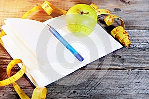 Planning of a diet. A notebook c an inscription - the Diet, a measuring tape, an apple and pen