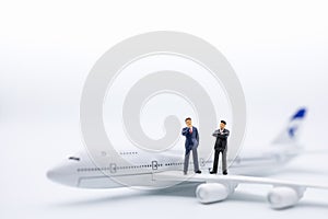 Planning and Global Business Concept. Close up of two businessman miniature figure standing on airplane wing o white background