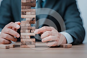 Planning, risk and strategy in business. Businessman holds the model of business, made from wood blocks. Alternative risk concept,