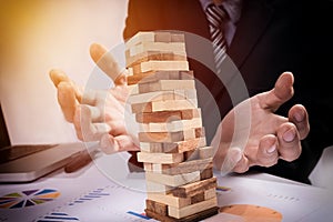 Planning, risk and strategy in business concept, businessman gambling placing wooden block on a tower