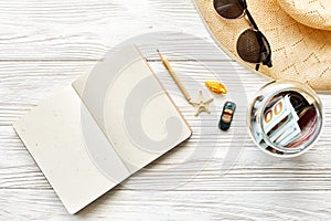 planning summer travel concept and wanderlust flat lay, space for text. empty notebook with pen money jar sunglasses hat shells c