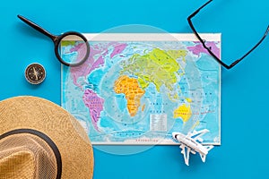 Planning a travel concept. Map of the world and tourist accessories on blue background top view