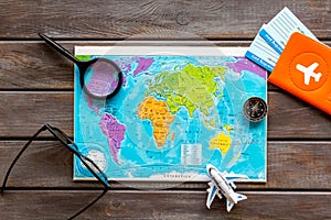 Planning a travel concept. Map of the world and tourist accessories on dark wooden background top view