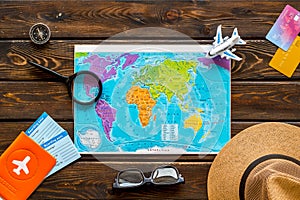 Planning a travel concept. Map of the world and tourist accessories on dark wooden background top view