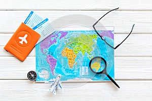 Planning a travel concept. Map of the world and tourist accessories on white wooden background top view