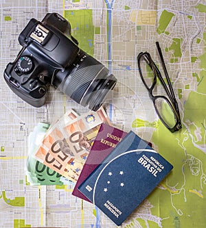 Planning a trip - Brazilian and Italian passports on city map with euro bills money, camera and glasses