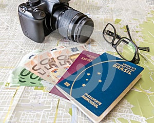 Planning a trip - Brazilian and Italian passports on city map with euro bills money, camera and glasses