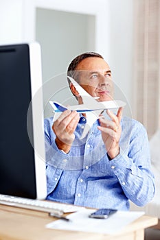 Planning trip - Happy mature man holding toy plane at home. Planning trip - Portrait of a happy mature man with toy