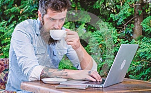 Planning vacation. Book apartment online. Man bearded hipster sit outdoors with laptop surfing internet and drinking