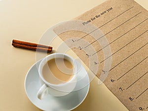 Plans for the new year. Text on craft paper and space for handwriting. Coffee and cinnamon on yellow background