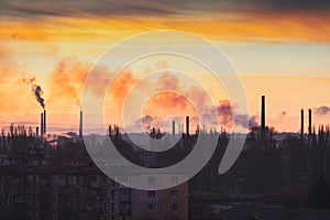 Plant or factory emissions seen above residential blocks of a city during sunrise or sunset. Environmental pollution. Panoramic