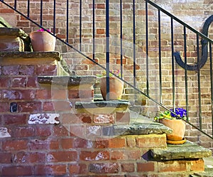 Plant pots stacked along a brick wall with railings country home