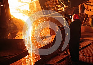 Plant for the production of steel. An electric melting furnace. Factory worker takes a sample for metal.