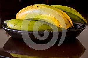 Plantain or Green Banana Musa x paradisiaca in a ceramic traditional dish on dark background