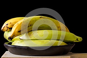 Plantain or Green Banana Musa x paradisiaca in a ceramic traditional dish on dark background photo
