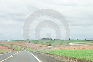 plantation with highway cutting through the scenery, splash of water wetting the planting and sky with rain clouds