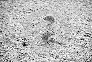 Planting in field. Little helper in garden. Boy planting flower in field digging ground. Work at farm. Mother nature