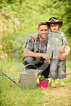 Planting flowers. Growing plants. Take care of plants. Boy and father in nature with watering can. Spring garden. Dad