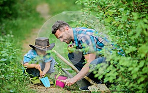 Planting flowers. Little helper in garden. Farm family. Little boy and father in nature background. Gardening tools