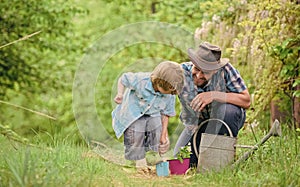 Planting flowers. Make planet greener. Growing plants. Take care of plants. Boy and father in nature with watering can