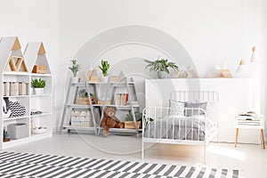 Plants and plush toy on shelves in scandi child`s bedroom interi