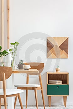 Plants in small vases on long wooden dining table in bright interior