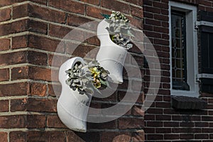 Plants in typical dutch wooden shoes on a brick wall