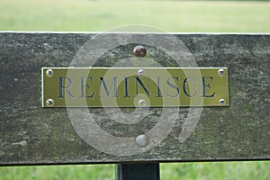 A plaque saying `reminisce` on a park bench