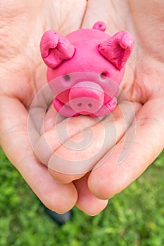 Plasteline piggy as moneybox in hands