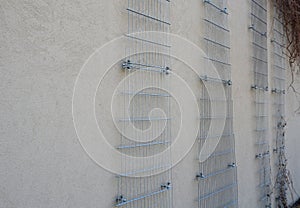 Plaster concrete wall on a house or factory. on the wall are attached galvanized grilles made of cheap mesh, which are full of cli