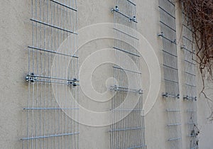 Plaster concrete wall on a house or factory. on the wall are attached galvanized grilles made of cheap mesh, which are full of cli