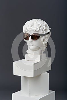 Plaster head of Antinous with round glasses. The concept of the absurd and the combination of the incongruous