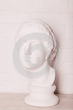 Plaster head of the statue against the background of a white brick wall