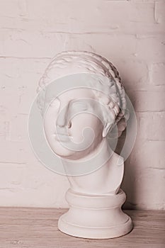 Plaster head of the statue against the background of a white brick wall