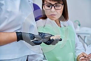 Plaster model of jaw in hands of doctor, female patient looking